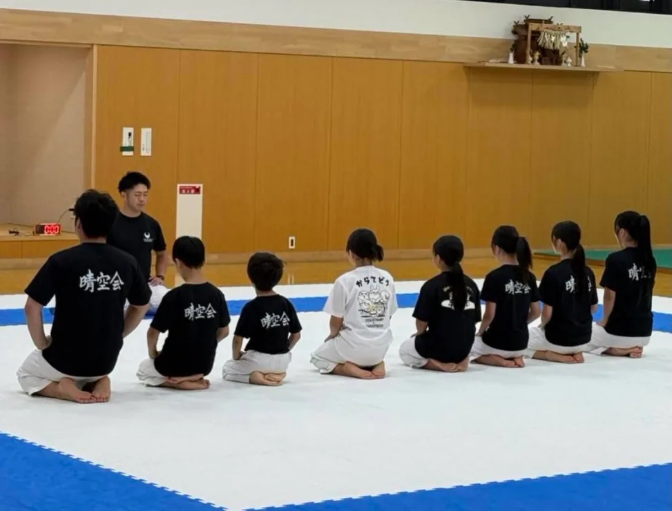稽古のはじめに正座して支部長の話を聞く道場生
